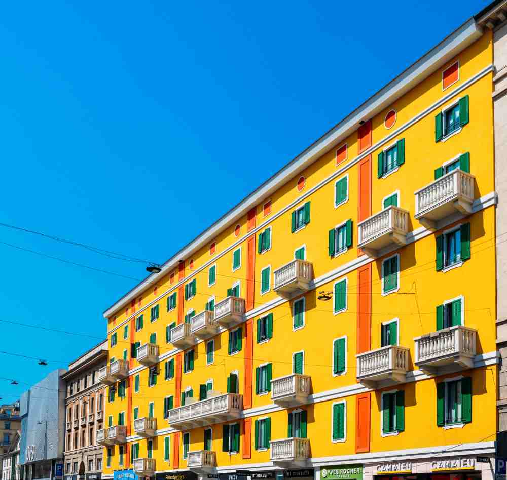 Fachada de un edificio residencial de color amarillo con balcones blancos, representativo de una comunidad de vecinos.